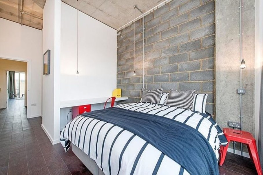 Industrial style London apartment - bedroom, bright furniture contrasts with the concrete wall